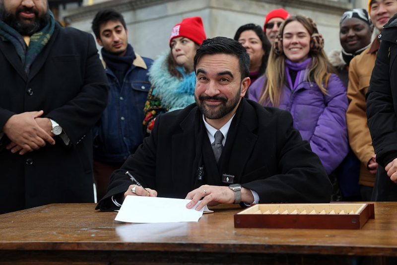 NEW YORK, NEW YORK - JANUARY 02: New York City Mayor Zohran Mamdani signs executive orders with campaign volunteers during an appearance at Grand Army Plaza in Brooklyn on January 02, 2026, in New York City. The newly inaugurated mayor has revoked a number of executive orders issued by former New York City Mayor Eric Adams, including some related to Israel. (Photo by Spencer Platt/Getty Images)