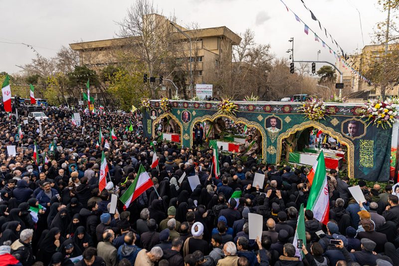 TEHRAN, IRAN - JANUARY 14: A crowd watches as the caskets of members of Iran's security forces, whom authorities said were killed during recent nationwide protests, are transported during a mass funeral on January 14, 2026 outside Tehran University in Tehran, Iran. The country has been gripped by a wave of anti-government protests and the ensuing crackdown, which rights groups say has left thousands of civilians dead. (Photo by Stringer/Getty Images)