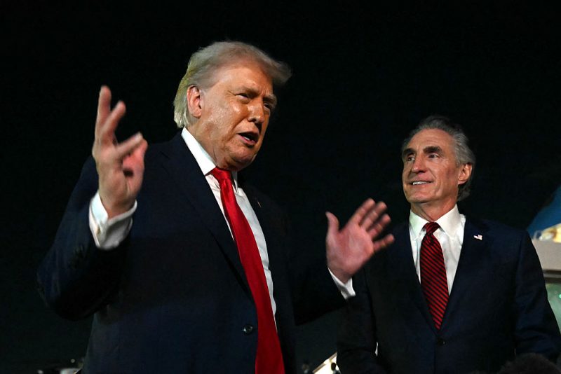 US President Donald Trump speaks with reporters as the Secretary of the Interior Doug Burgum (R) looks on, before boarding Air Force One at Palm Beach International Airport, in West Palm Beach, Florida on January 19, 2026. President Trump is returning to Washington after spending the weekend at his Mar-a-Lago residence and attending the College Football National Championship Game between Miami Hurricanes and Indiana Hoosiers at Hard Rock Stadium in Miami Gardens, Florida. (Photo by ANDREW CABALLERO-REYNOLDS / AFP via Getty Images)
