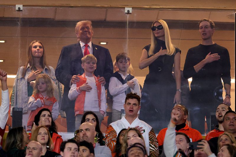 MIAMI GARDENS, FLORIDA - JANUARY 19: U.S. President Donald Trump stands for the National Anthem with his family prior to a game between the Miami Hurricanes and the Indiana Hoosiers in the 2026 College Football Playoff National Championship at Hard Rock Stadium on January 19, 2026 in Miami Gardens, Florida. (Photo by Alex Slitz/Getty Images)