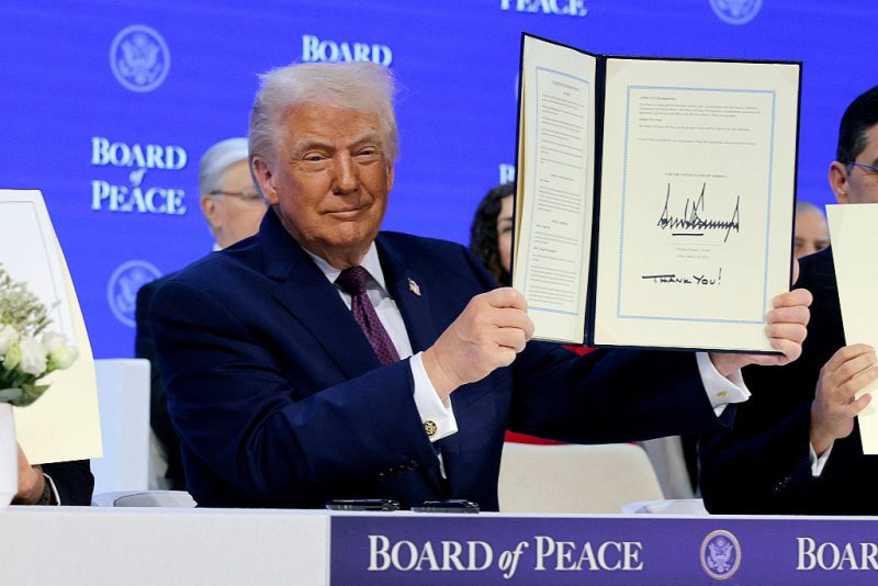 DAVOS, SWITZERLAND - JANUARY 22: U.S. President Donald Trump holds up his signature on the founding charter during a signing ceremony for the “Board of Peace” at the World Economic Forum (WEF) on January 22, 2026 in Davos, Switzerland. The US-backed “Board of Peace” is intended to administer the fragile ceasefire in the Gaza Strip after the war between Israel and Hamas. The final makeup of the board has not been confirmed. (Photo by Chip Somodevilla/Getty Images)