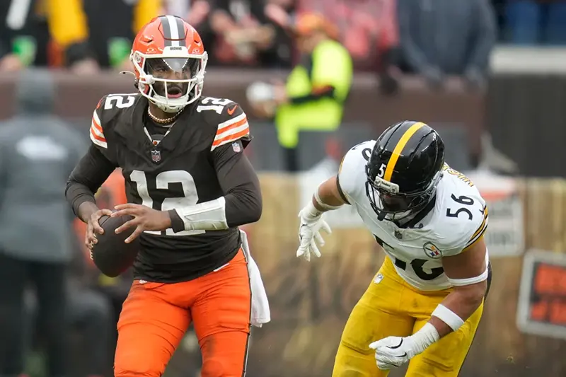 Cleveland Browns quarterback Shedeur Sanders (12) runs from Pittsburgh Steelers linebacker Alex Highsmith (56) during the second half of an NFL football game, Sunday, Dec. 28, 2025, in Cleveland. (AP Photo/Sue Ogrocki)