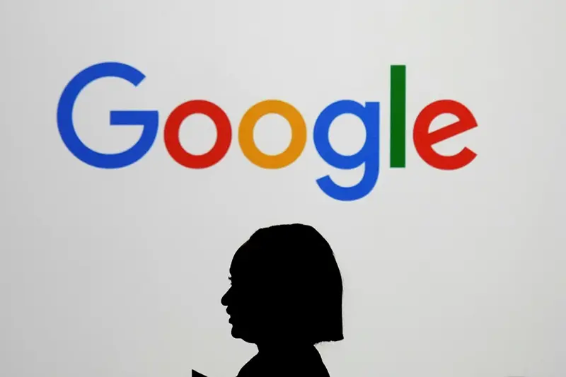 A woman walks by a giant screen with a logo at an event at the Paris Google Lab on the sidelines of the AI Action Summit in Paris, on Feb. 9, 2025. (AP Photo/Thibault Camus,File)