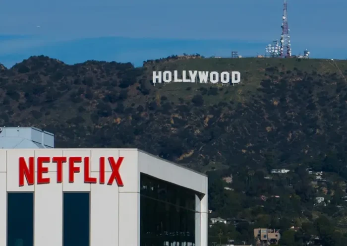 A Netflix sign is displayed atop a building in Los Angeles, on Dec. 18, 2025, with the Hollywood sign in the distance. (AP Photo/Jae C. Hong, File)