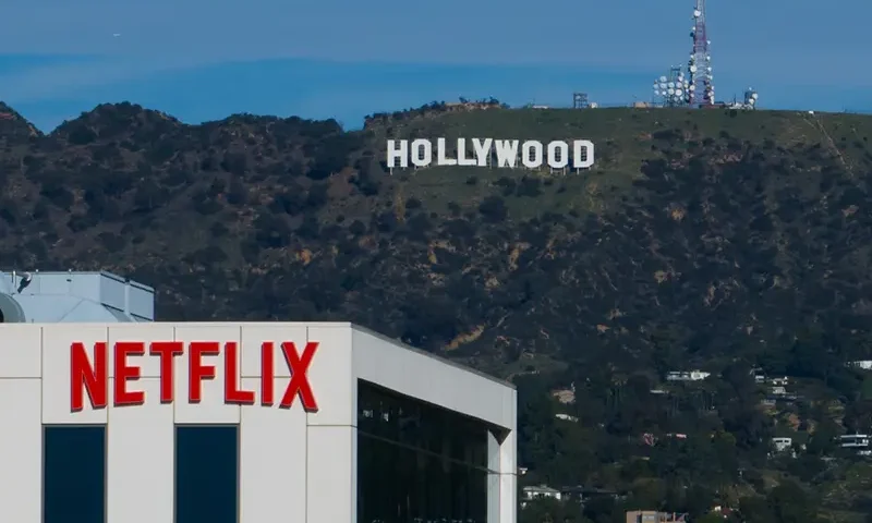 A Netflix sign is displayed atop a building in Los Angeles, on Dec. 18, 2025, with the Hollywood sign in the distance. (AP Photo/Jae C. Hong, File)