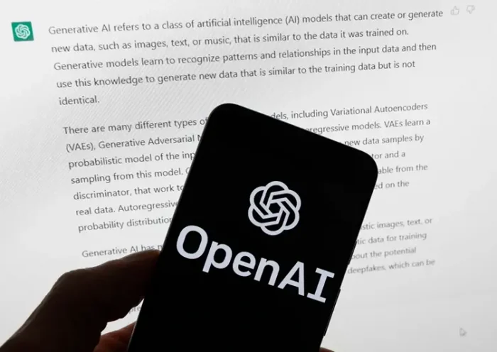 The OpenAI logo is displayed on a mobile phone in front of a computer screen with output from ChatGPT, March 21, 2023, in Boston. (AP Photo/Michael Dwyer, File)