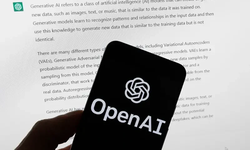 The OpenAI logo is displayed on a mobile phone in front of a computer screen with output from ChatGPT, March 21, 2023, in Boston. (AP Photo/Michael Dwyer, File)