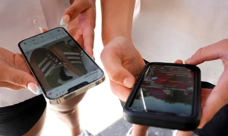 Young people use their phones to view social media in Sydney, Nov. 8, 2024. (AP Photo/Rick Rycroft, File)