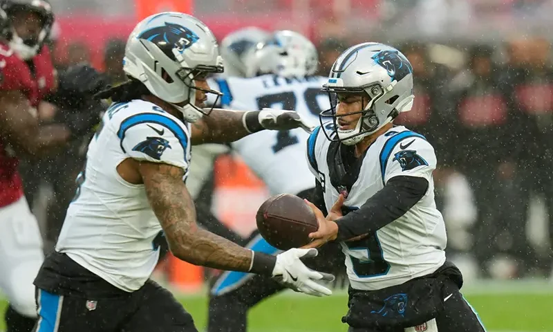 Carolina Panthers quarterback Bryce Young, right, hands off to running back Rico Dowdle (5) during the first half of an NFL football game Saturday, Jan. 3, 2026, in Tampa, Fla. (AP Photo/Chris O’Meara)