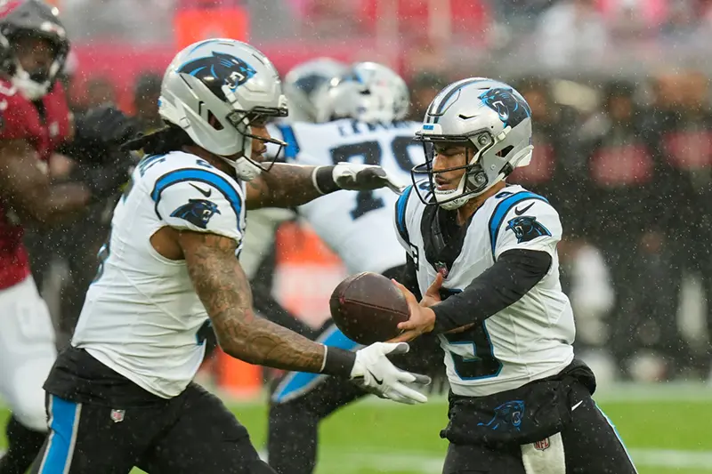 Carolina Panthers quarterback Bryce Young, right, hands off to running back Rico Dowdle (5) during the first half of an NFL football game Saturday, Jan. 3, 2026, in Tampa, Fla. (AP Photo/Chris O’Meara)