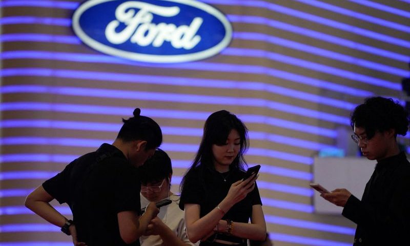 People stand near a logo of Ford at the Auto Shanghai show, in Shanghai, China April 18, 2023. REUTERS/Aly Song/File Photo
