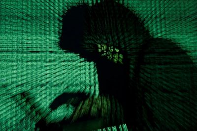 Man holds laptop computer as cyber code is projected on him in this illustration picture. File: Kacper Pempel/Reuters