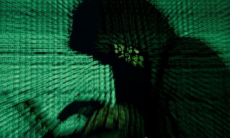 Man holds laptop computer as cyber code is projected on him in this illustration picture. File: Kacper Pempel/Reuters