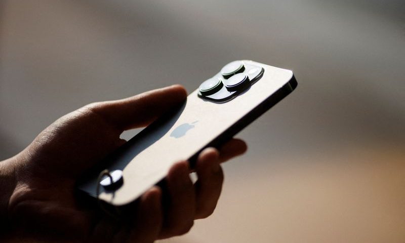 FILE PHOTO: A man holds an iPhone 14 as Apple Inc's new models go on sale at an Apple store in Beijing, China, September 16, 2022. REUTERS/Thomas Peter/File Photo